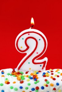 Number two birthday candle on red background